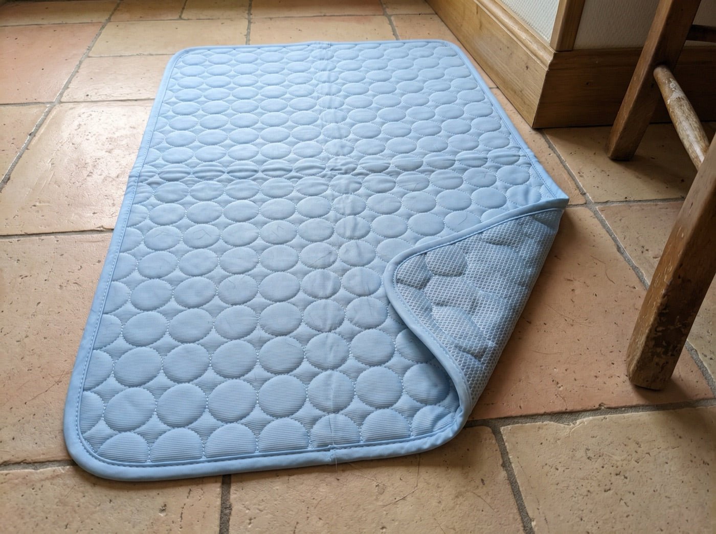 Le tapis rafraîchissant à plat, un coin replié montrant le filet du dessous